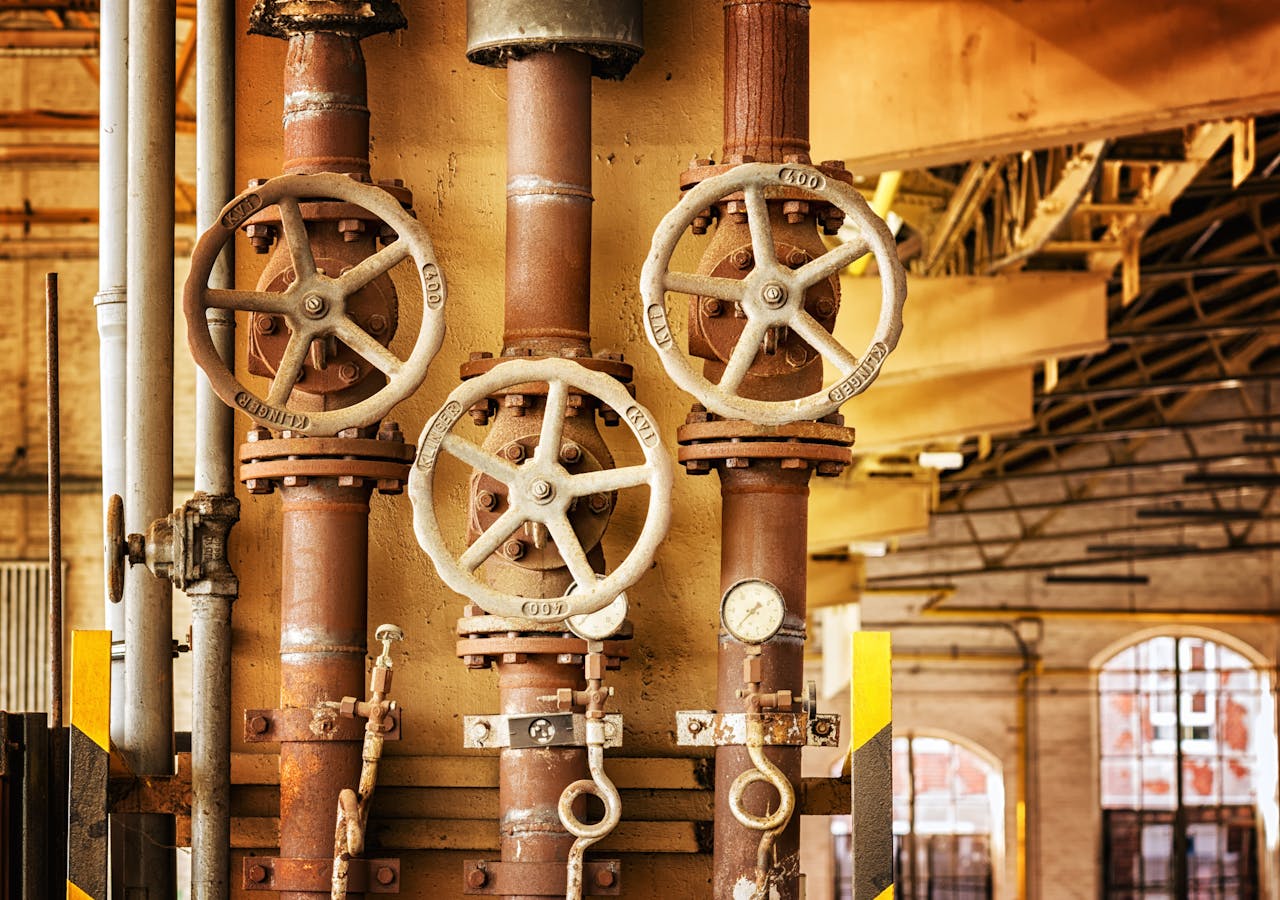 A photograph of a several pipes in parallel, each with a wheel-turned valve.